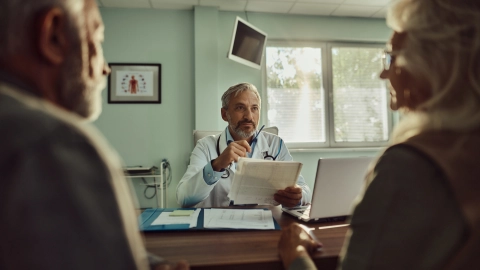 Мужчина и женщина беседую с врачом в медицинском кабинете.